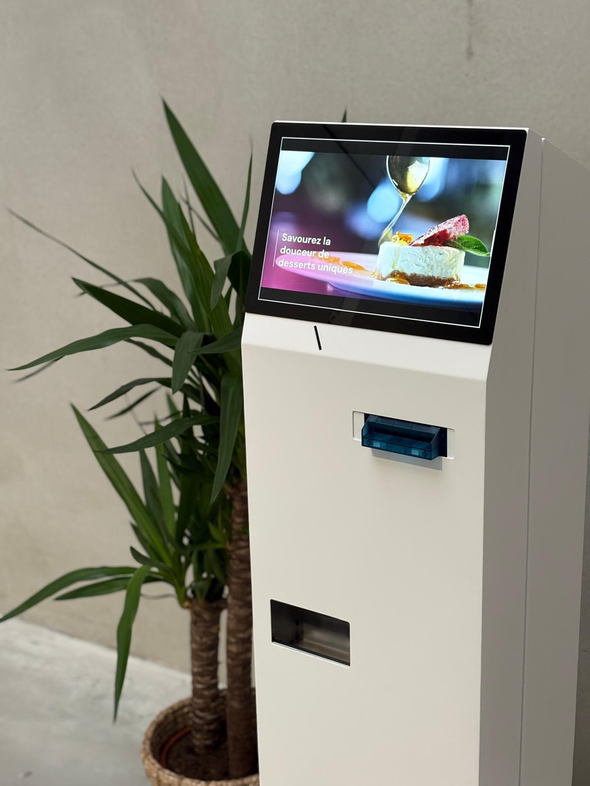 Automatische muntautomaat CashSystem geïnstalleerd in een Belgische winkel — witte kiosk met touchscreen en biljettenlade