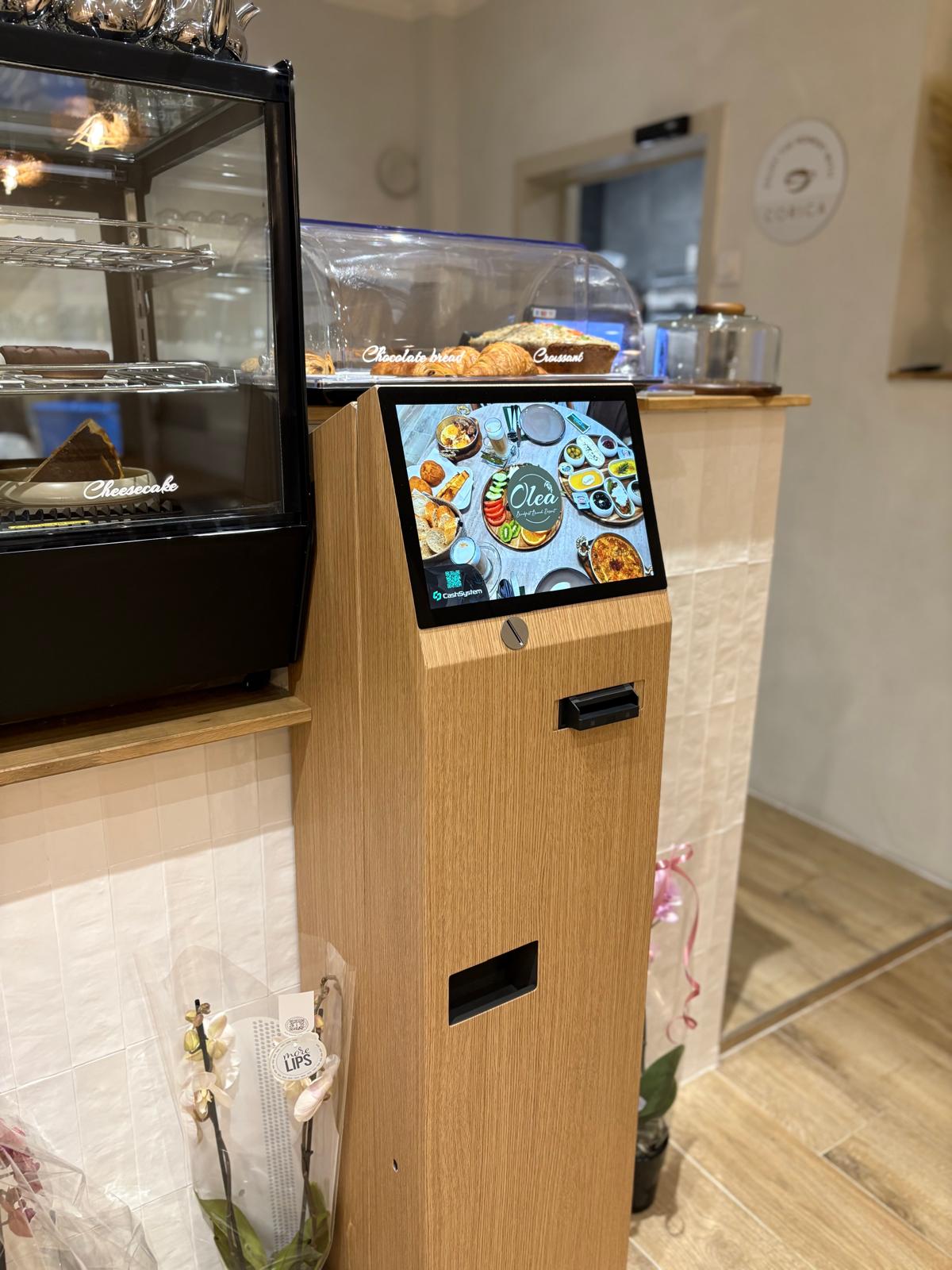 Monnayeur CashSystem chez Olea — habillage bois chêne